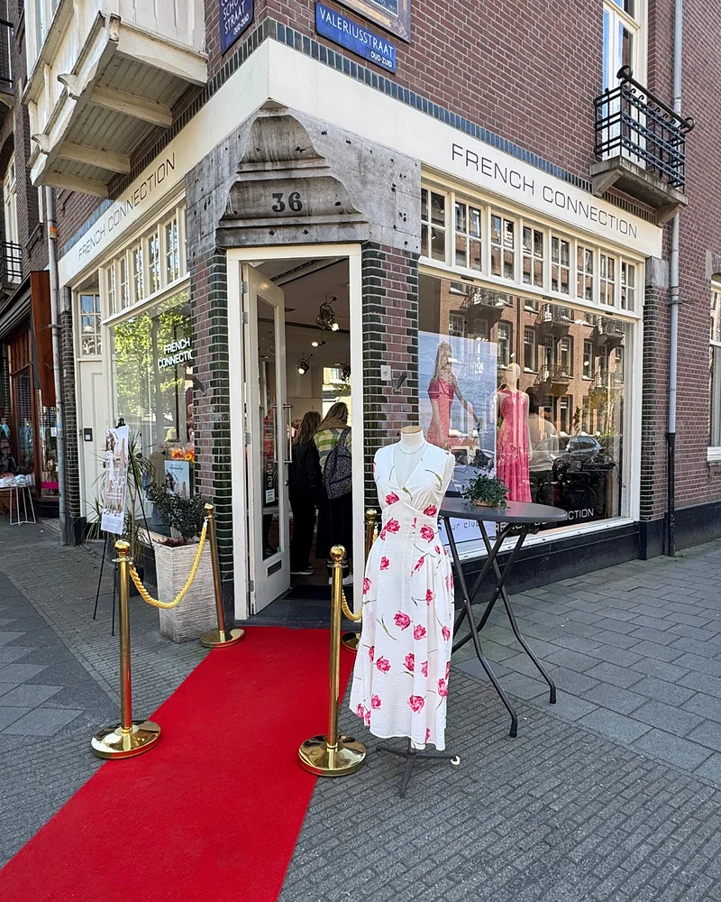 The French Connection store at Cornelis Schuytstraat 36 in Amsterdam, with a red carpet and a floral dress from the SS26 collection outside