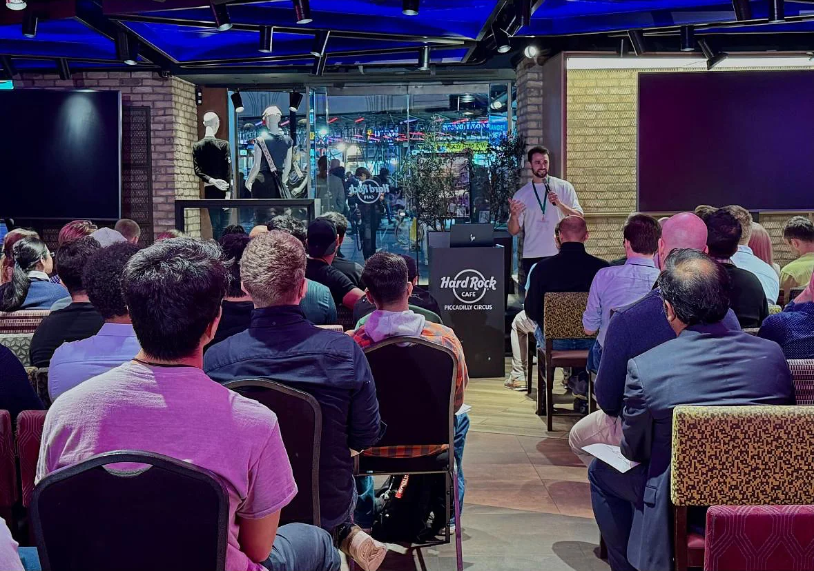 A StyleAI co-founder speaking to a seated audience at the AI Agents World Tour at Hard Rock Cafe Piccadilly Circus in London